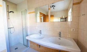 A modern bathroom with two sinks and large mirrors. A separate shower is also available.
