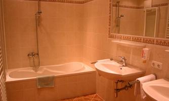 A modern bathroom with a bathtub and a sink. The walls are brightly tiled and a large mirror hangs above the sink.