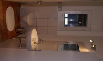 A modern bathroom with a toilet and a sink. A window provides daylight.