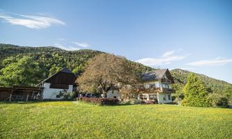 A tranquil rural estate with a large green garden and gentle hills in the background. The weather is sunny and clear.