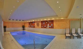 An elegant indoor pool with blue water and modern loungers. The walls are decorated with stylish artworks.