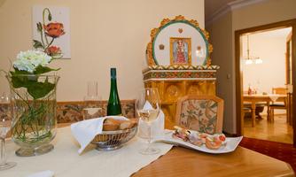 A beautifully set table with a bottle of sparkling wine, glasses, and a plate of delicious snacks. In the background, there is an artistic wall decoration and an inviting dining area.