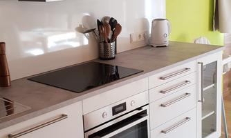 A modern kitchen with white cabinets and a clean, bright design. The walls are painted in a fresh shade of green.