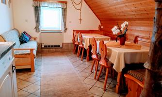 A cozy room with wooden walls and tiled floors. There is a dining area with tables and chairs, as well as a seating area with a sofa.