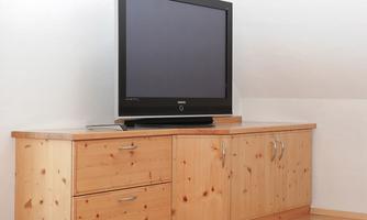 A piece of wooden furniture with a large television on it. The furniture is light and kept simple.