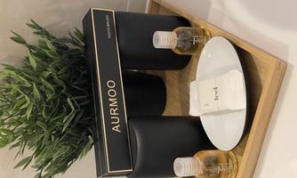 An elegant tray with large black containers, two bottles of oil, and a small plate with napkins. In the background, there is a green plant.