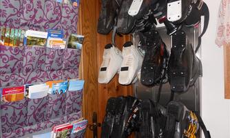 A room with a door, on which a row of skates hangs. Next to it is a bag with tourist brochures.