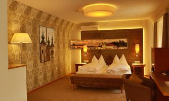 A modern hotel room with warm lighting and elegant decor. The room contains two beds, a desk, and decorative wall art.