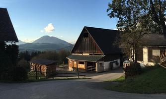 A rural scene with a traditional farmhouse and gentle hills in the background. The sky is clear and the landscape appears peaceful.