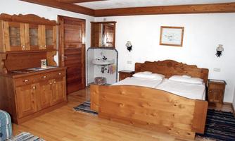 A cozy bedroom with wooden furniture and a double bed. The room has a warm, inviting character and offers a rustic atmosphere.