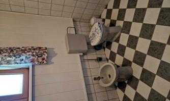 A bathroom with a modern toilet and a bidet. The floor consists of a black-and-white tile pattern.