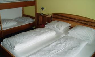 A simple bedroom with a double bed and a bunk bed. The bedding is clean and tidy.