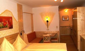 A cozy room with wooden decor and comfortable beds. The room includes a dining area and a kitchen.