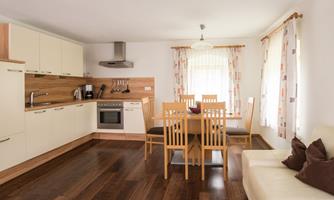 A modern kitchen with a dining table and chairs. Bright walls and wooden flooring create an inviting atmosphere.