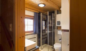 A modern bathroom with wooden paneling and a large glass shower. It also includes a sink and a toilet.