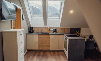 <p>A modern kitchen with wood and a refrigerator in a bright room. Large windows offer a view of the mountains.</p>