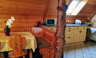 A cozy kitchen with wooden walls and a small dining nook. The room is brightly lit by a skylight.