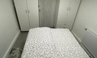 A simple bedroom with a double bed and a large wardrobe. The room is bright and modernly furnished.
