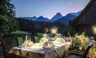A beautiful outdoor area with a covered table and mountain view. The sky is wrapped in soft hues of dusk.