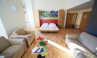 A cozy room with two single beds and modern furniture. The space is bright with wooden flooring and offers a relaxed atmosphere.