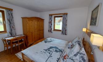 A cozy bedroom with a double bed and wooden wardrobes. Two windows provide plenty of daylight and an inviting atmosphere.