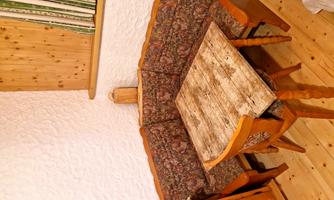 A cozy seating area with a table and a padded bench. The walls are light, and there are wooden elements in the room.