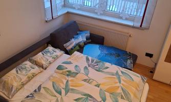 A cozy bedroom with a bed and colorful pillows. The window is adorned with a curtain that lets in a lot of light.