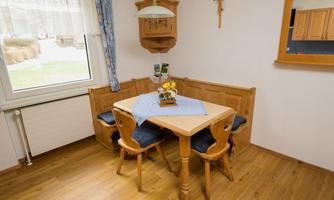 A cozy dining area with a wooden table and chairs. Large windows let in plenty of light and provide a view outside.