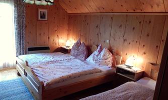 A cozy bedroom with wooden ceilings and two beds. There is soft lighting and a view out of the window.
