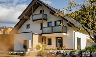 A modern house with two floors and large windows. The garden is well-maintained and designed with stones.