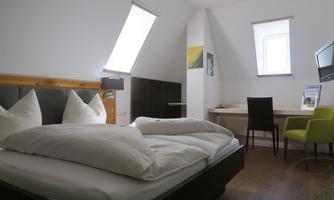 A cozy room with a double bed, large windows, and a desk. The decor is modern and inviting.