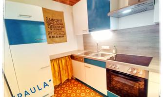 A modern kitchen with blue and white cabinets. A decorative sign with a coffee motif hangs on the wall.