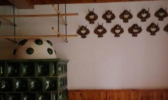 A cozy room with a traditional stove and a wooden bench. Decorative wall plates hang on the wall.