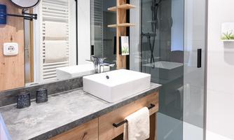 A modern bathroom with an elegant wooden vanity top and a stylish sink. There is a glass shower and bright walls that give the room an inviting atmosphere.