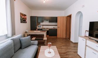 A modern living room with a cozy couch and a small dining table. The kitchen is well-equipped, and the rooms are bright and cheerfully designed.