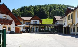 A charming hotel building with traditional architecture, surrounded by green hills. The entrance area is inviting and well-designed.