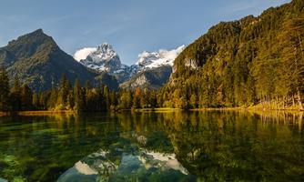 A picturesque mountain lake, surrounded by towering mountains and forests. The clear water surface reflects the majestic landscape.