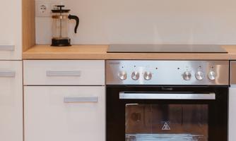 A modern kitchen with a stove and an elegant, smooth surface. The cabinets are simple and in light colors.