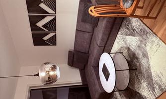 A cozy living room with a gray corner sofa and a round table. Modern pictures are hanging on the wall and there is an elegant chandelier.
