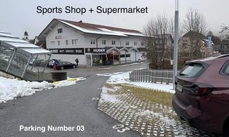 A sporting goods store and a supermarket are visible in a building. There is also a parking lot with free parking spaces.