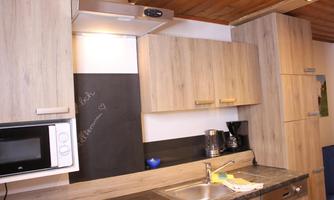 A modern kitchen with wooden cabinets and an elegant countertop. On the counter, there is a coffee machine and a microwave.