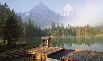A tranquil lake surrounded by mountains and dense forests. The fog gives the scene a mystical atmosphere.