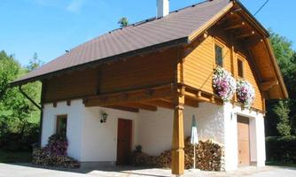 A beautiful wooden house with a white facade and a black roof. Blooming plants adorn the windows and the entrance area is inviting.