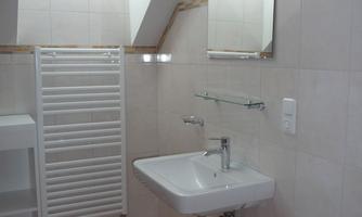 A modern bathroom with a sink, a large mirror, and a towel warmer. The skylight provides plenty of natural light.