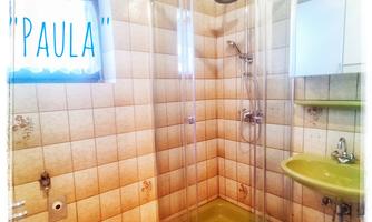 A modern bathroom with a shower and a sink. The walls are tiled and the floor has an interesting design.