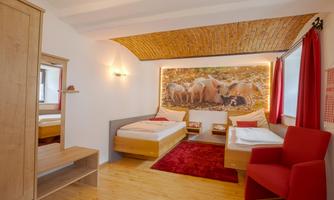 A cozy room with two beds and a red carpet. A large picture of pigs in nature hangs on the wall.