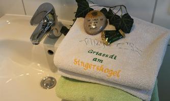 A sink with a modern faucet. Hand-stitched towels are placed on it along with a small decoration featuring a stone and green leaves.