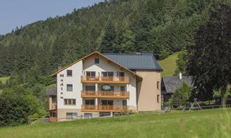 A modern house nestled among green hills. The surroundings are quiet and surrounded by trees.