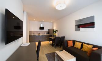 A modern kitchen-living room with a cozy sofa and a dining area. The space is bright and friendly designed.