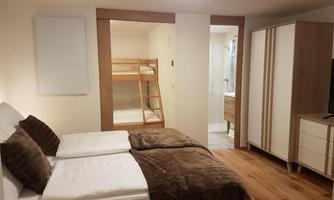 A cozy bedroom with a double bed and a bunk bed. The room is bright and modernly furnished.